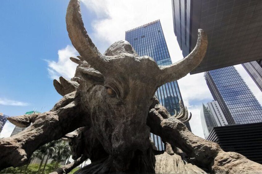 A large bull statue with horns, set against a backdrop of modern skyscrapers. 4