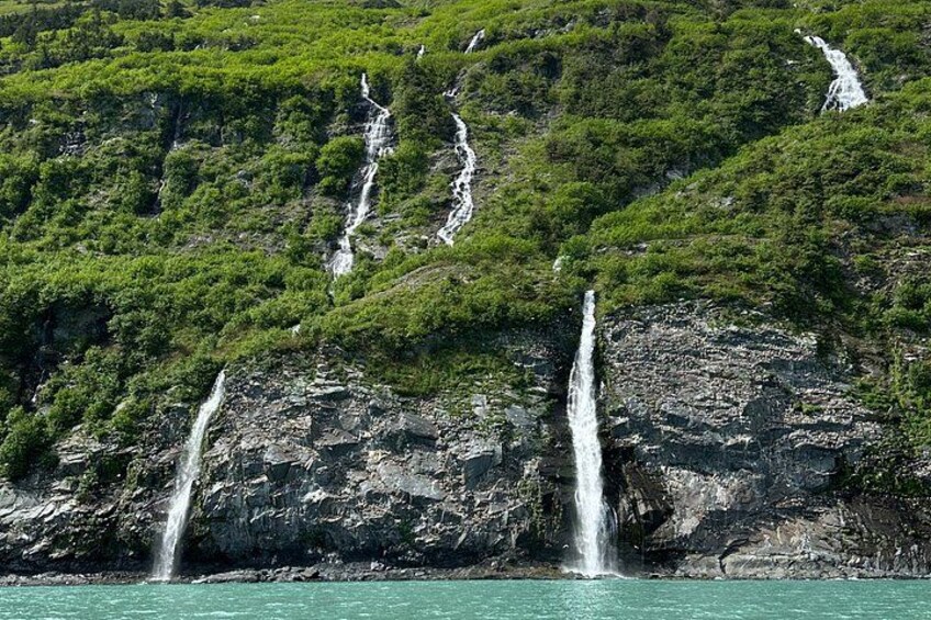 A waterfall cascading down a rocky cliff surrounded by lush greenery. 3