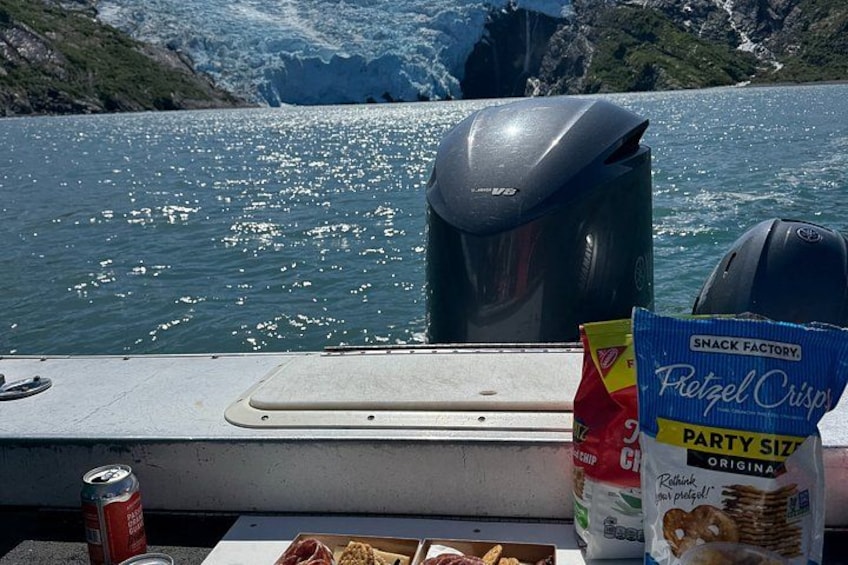 A boat with snacks and a can on the deck, water and mountains in the background. 4