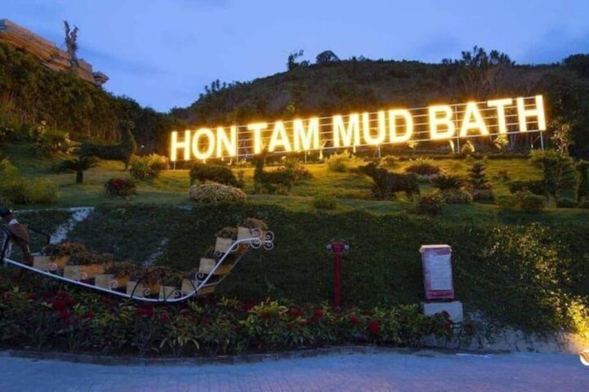 A sign reading 'HON TAM MUD BATH' with a camel sculpture in the foreground. 3