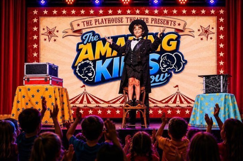 A stage with a performer in a black suit, a circus tent backdrop, and an audience. 2