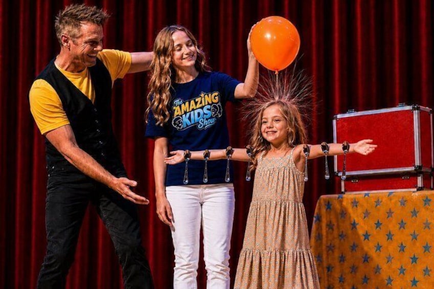 A stage with a red curtain backdrop, a red box, and a person in a yellow shirt. 5