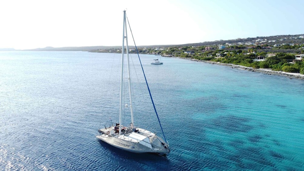 A sailboat named 'TUCANSPACE' on a calm sea with a coastal town in the background. 2