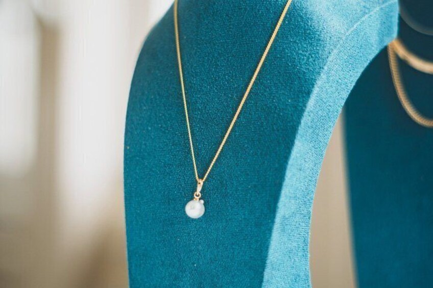 A mannequin wearing a gold necklace with a pendant. 2