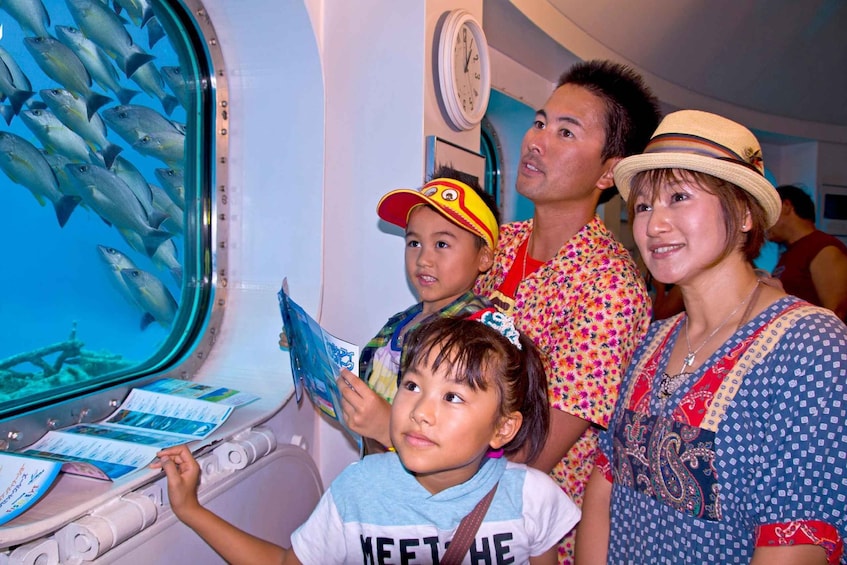 A group of people observing fish through an aquarium window. 2