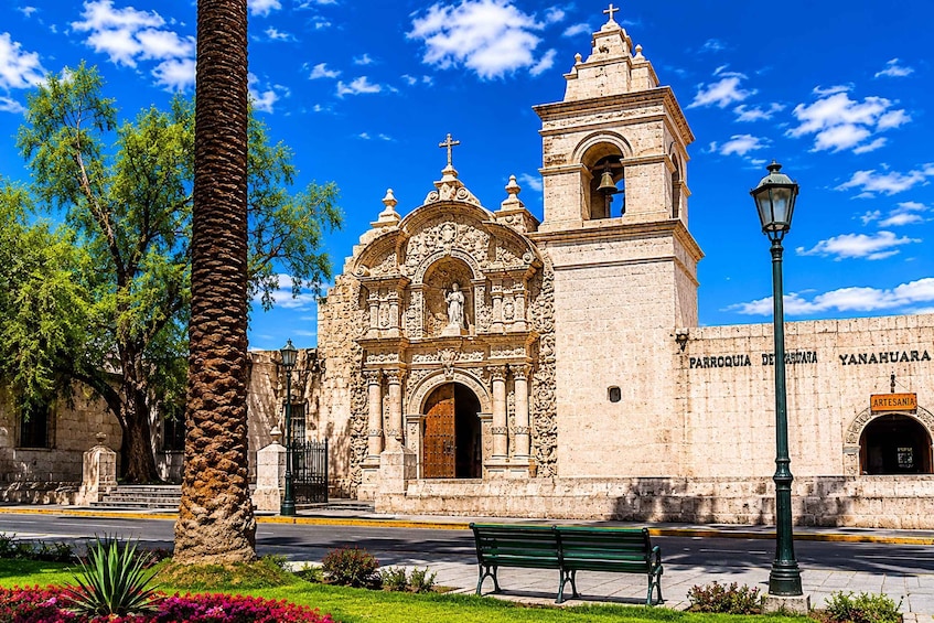 A historic church with a bell tower, a street lamp, and a bench in front. 2