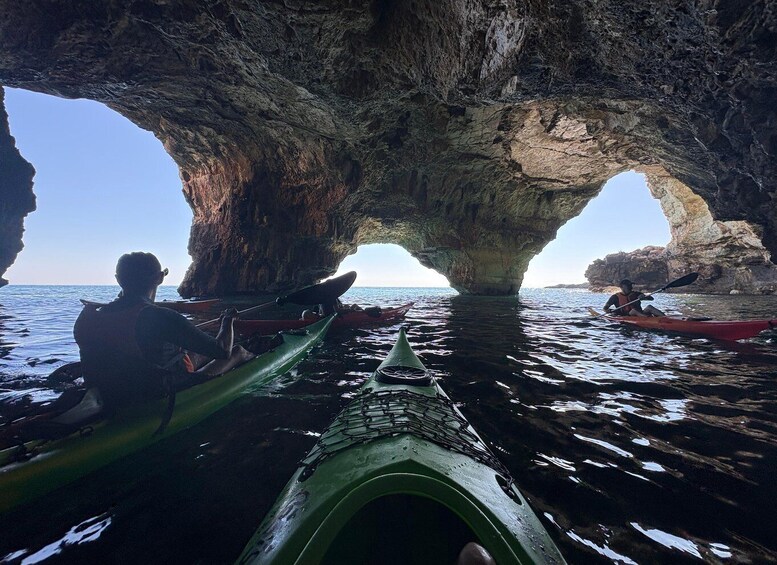 Kayakers in a cave opening with water. 1