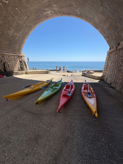 A stone archway leading to a beach with kayaks lined up on the sand. 2