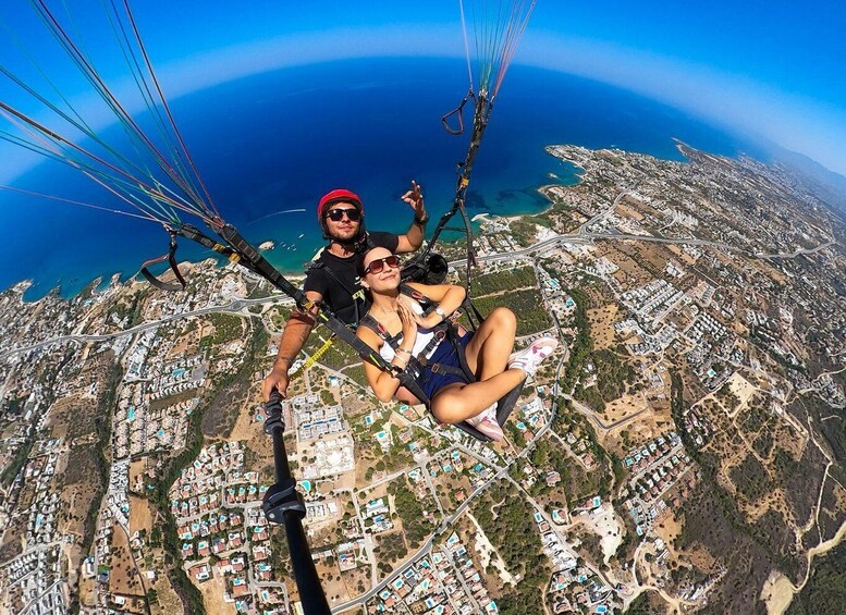 A person and a woman paragliding over a coastal cityscape. 1