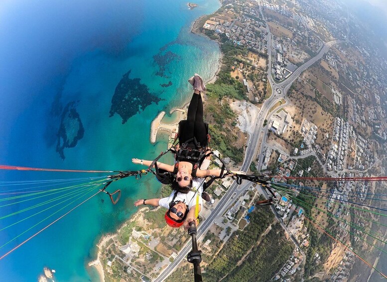 A person skydiving with a parachute above a coastal cityscape. 4
