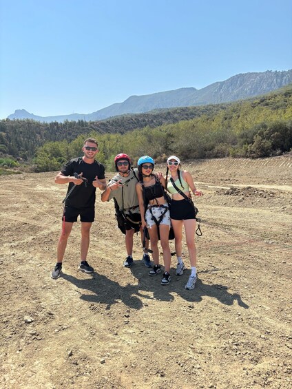 Four people hiking in a dry, rocky terrain with mountains in the background. 2