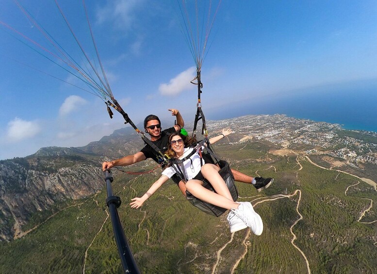 Two people paragliding over a mountainous landscape with a coastal city in the background. 5