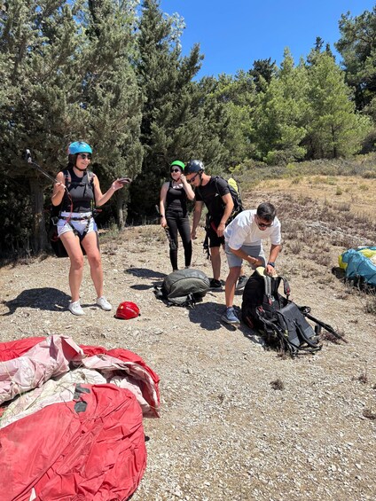 A group of people preparing gear in a rocky outdoor setting with trees in the background. 3