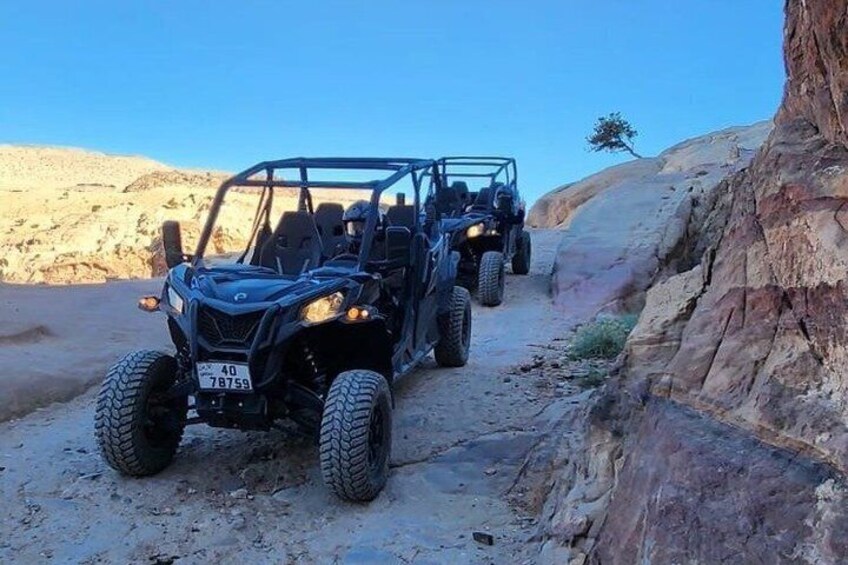 Two off-road vehicles on a dirt trail in a rocky desert landscape. 1