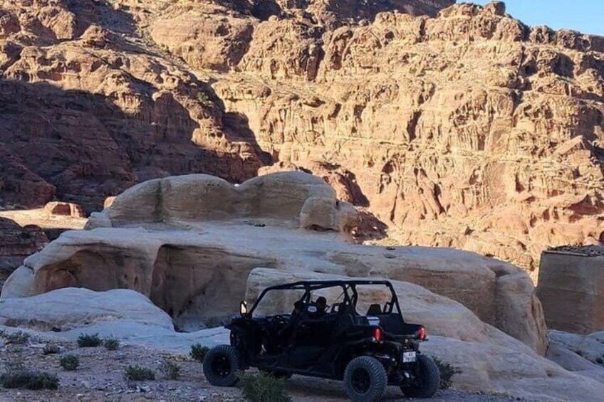 A black off-road vehicle parked on rocky terrain with a desert landscape in the background. 5