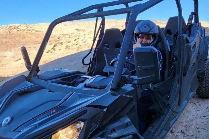 A black off-road vehicle with a driver, desert landscape, and clear sky. 2