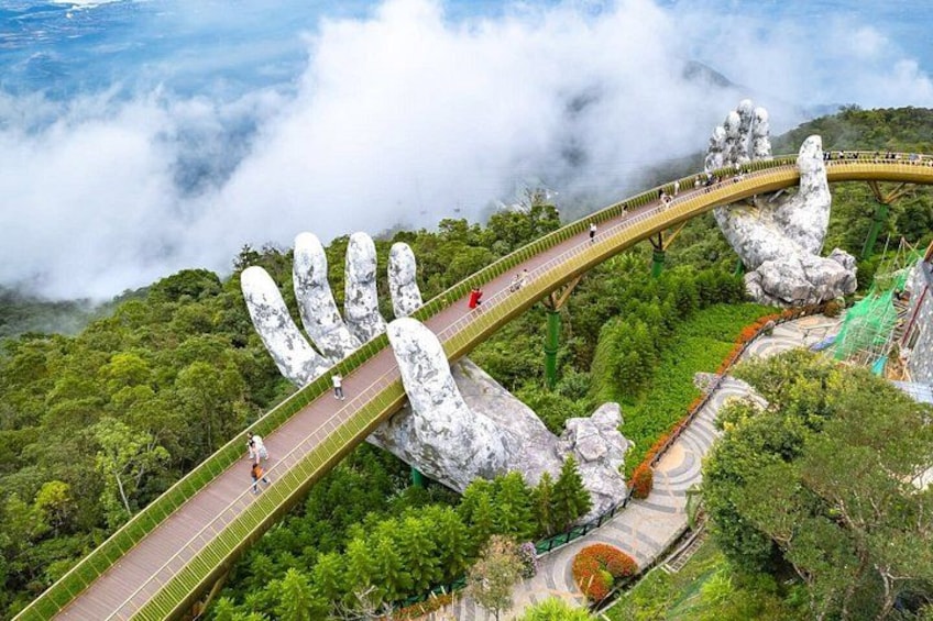 A bridge with a hand-shaped design, surrounded by lush greenery and clouds. 1