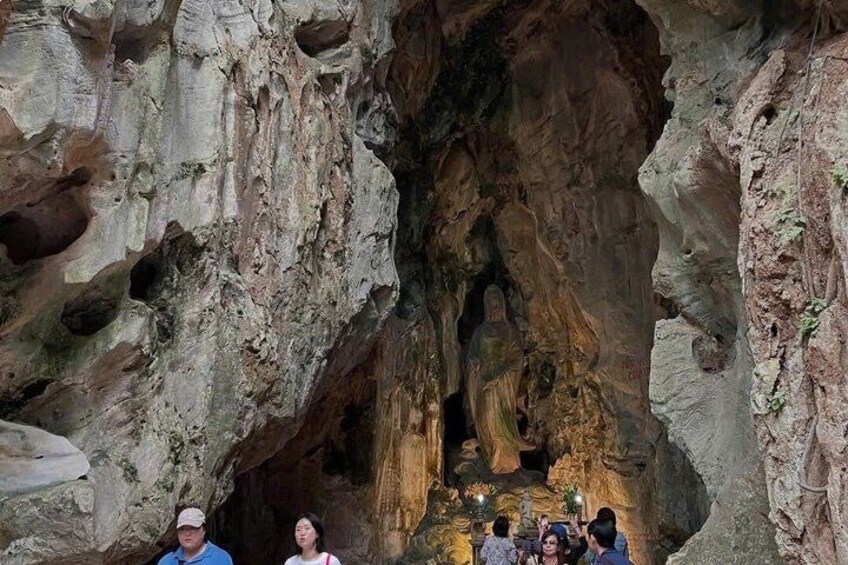 A cave with stalactites and stalagmites, and people observing the formations. 4