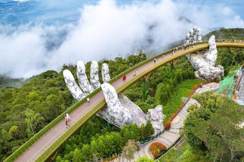A bridge with a hand-shaped design, surrounded by lush greenery and clouds. 1