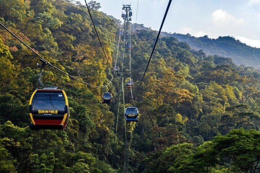 A cable car system in a forested area with lush greenery and hills in the background. 3