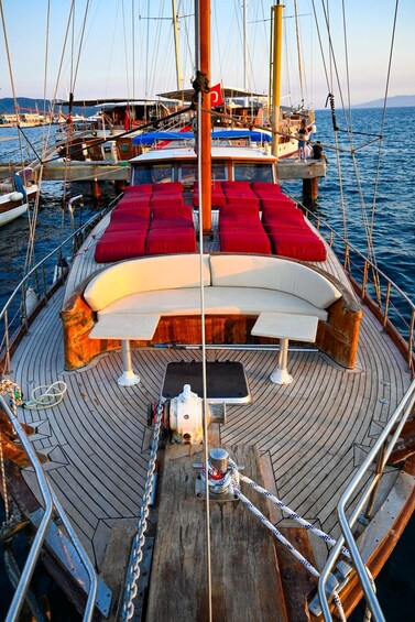 A boat deck with red cushions, a white sofa, and a table. 2