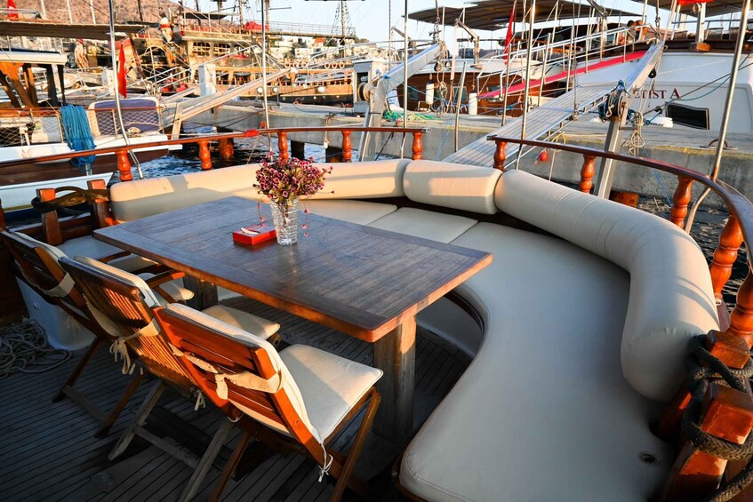 A wooden deck with a curved seating area, a table, and a vase with flowers. 5