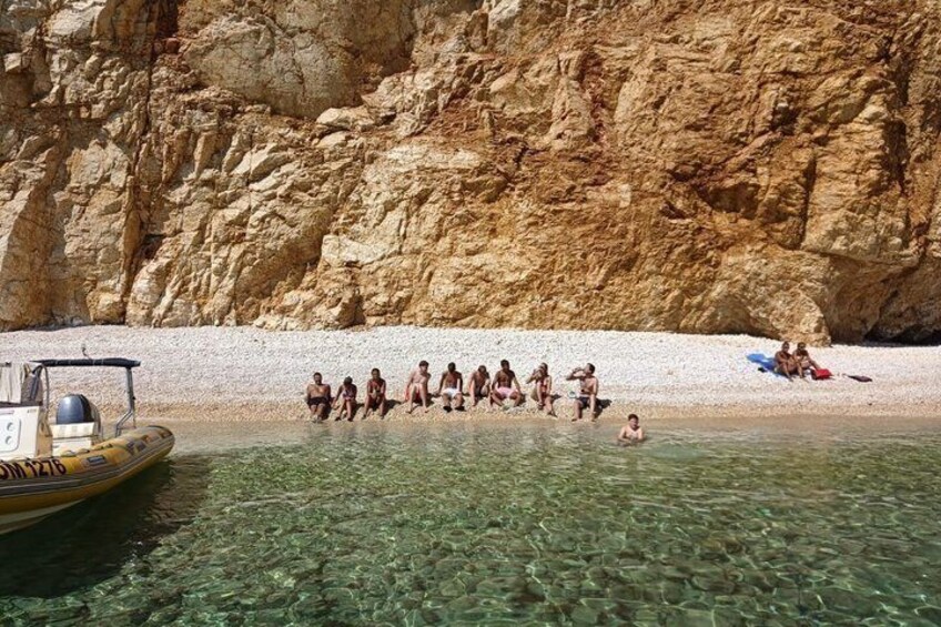A group of people on a beach with a rocky cliff in the background. 4