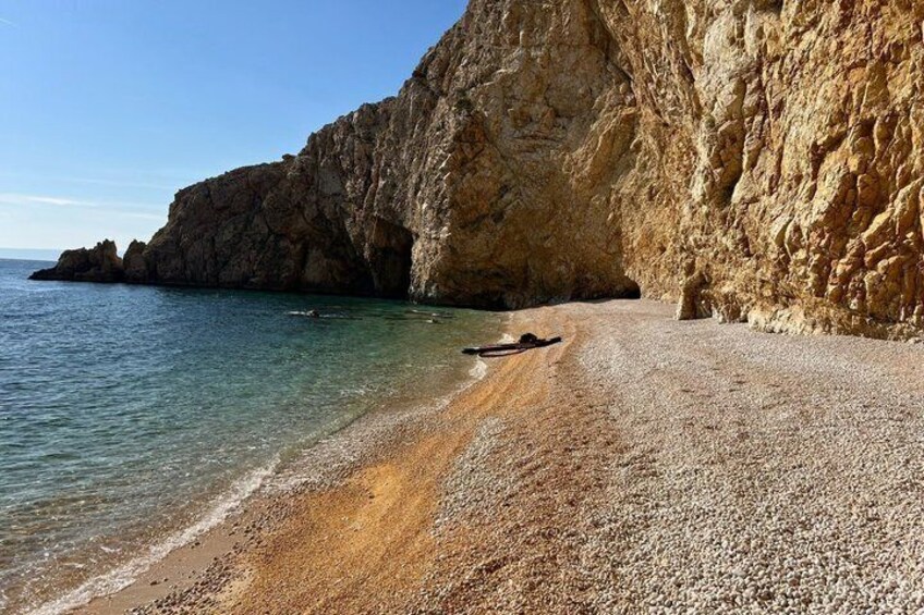 A rocky beach with clear water and a large cliff. 5