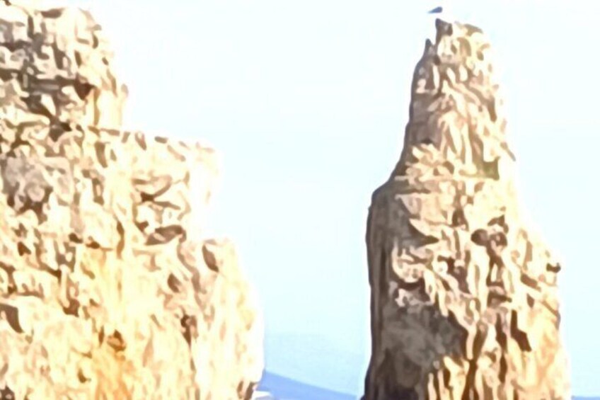 A rocky cliff with a bird perched on top. 3