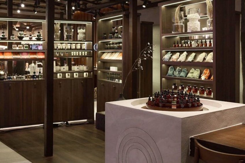 A store interior with shelves of shoes and handbags, a central display table, and wooden shelving units. 3