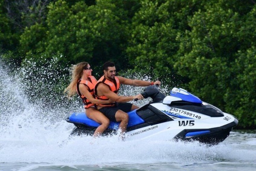 A person riding a jet ski on water with trees in the background. 1