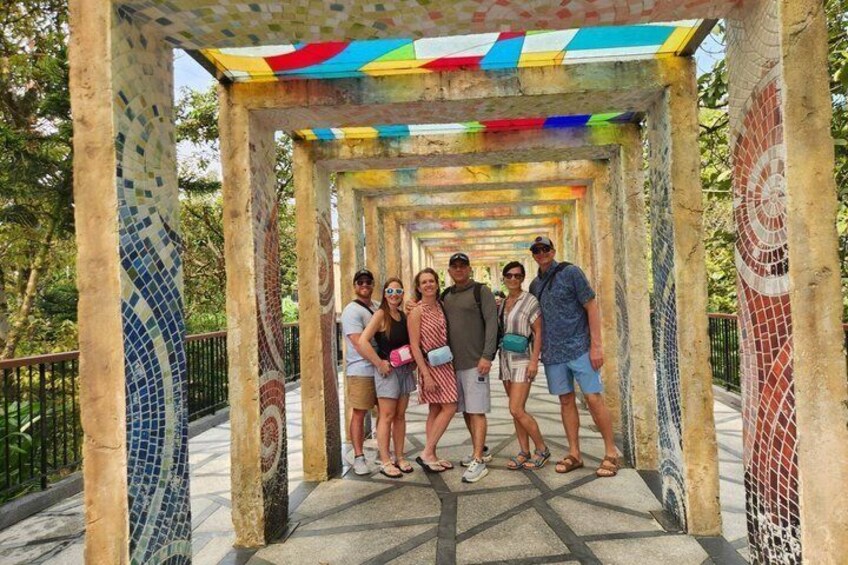 A group of people standing under a colorful, mosaic-tiled structure with a patterned floor. 5