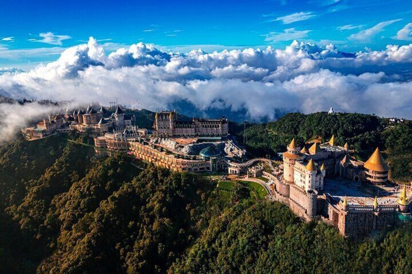 A castle complex surrounded by lush greenery and clouds. 1