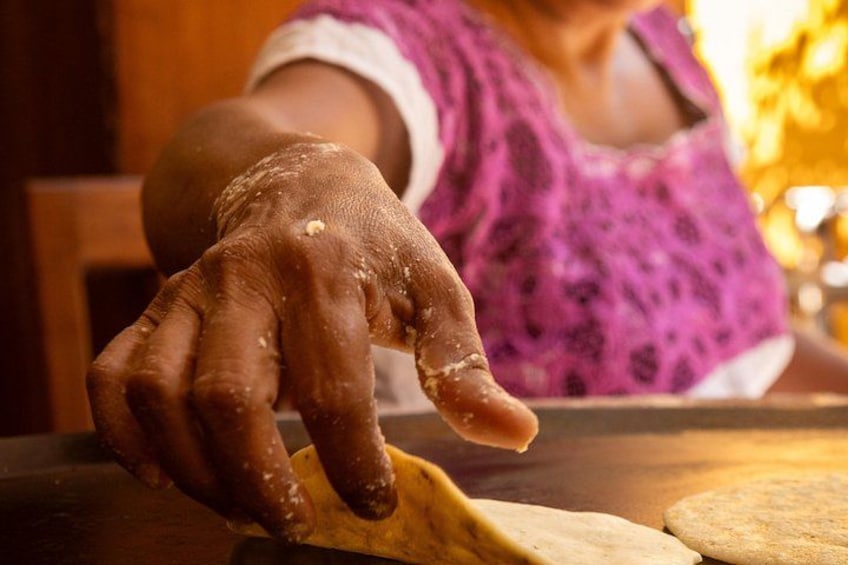 A person with a hand covered in flour, kneading dough on a wooden surface. 2