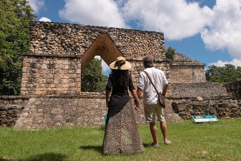 A stone structure with an arched doorway, a grassy area, and a clear sky. 5
