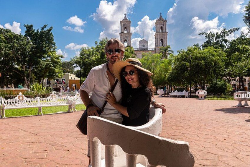 A couple sitting on a bench with a historic church in the background. 1