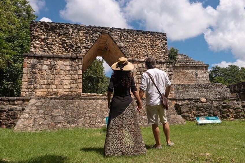 Two people standing in front of an ancient stone structure with a large wooden archway. 5