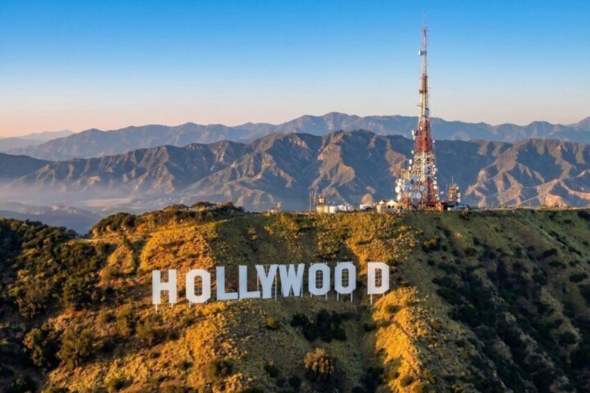 A Hollywood sign on a hill with a radio tower in the background. 1