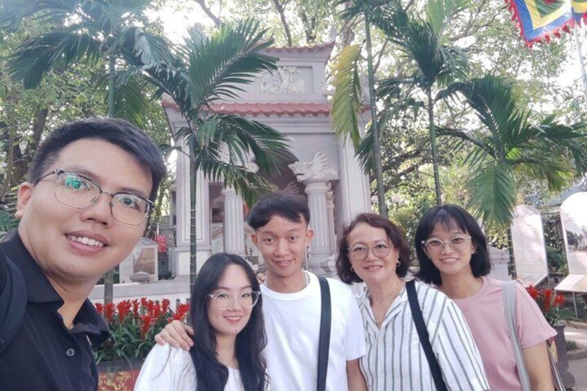 A group of people posing in front of a historical building with columns and a red flower arrangement. 4