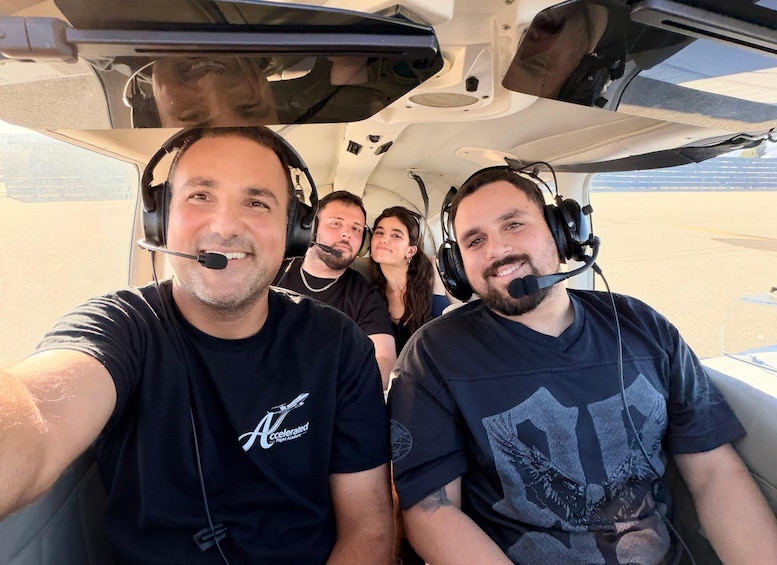 Tre personer i ett cockpit, alla med hörlurar och t-shirts med logotyper på. 2
