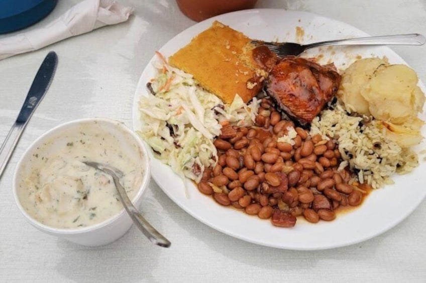 A plate of food with beans, rice, coleslaw, and a meat dish. 2