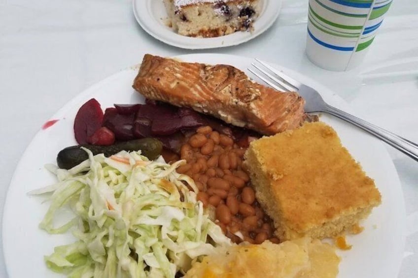 A plate with salmon, beans, coleslaw, beets, and a piece of cornbread. 3