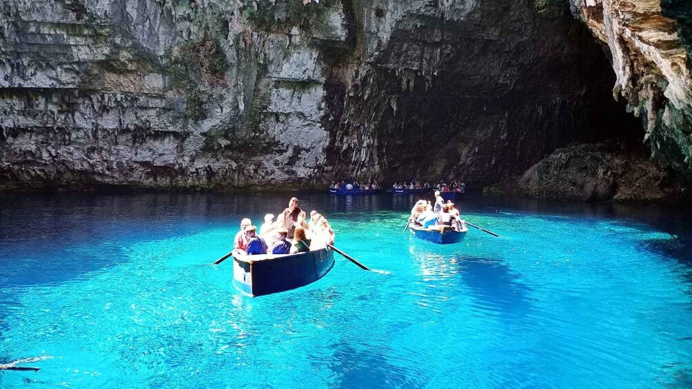 Two boats with passengers on a clear blue water body surrounded by rocky cliffs. 2