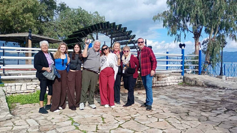 A group of people posing in front of a stone pathway with a railing and trees in the background. 4