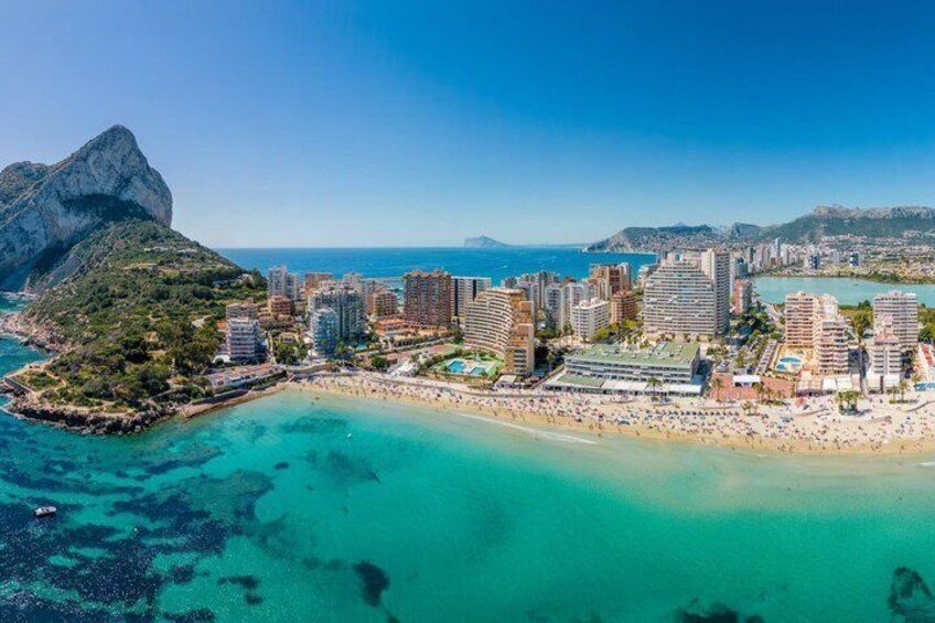 A coastal cityscape with a prominent mountain, a beach, and a marina. 1