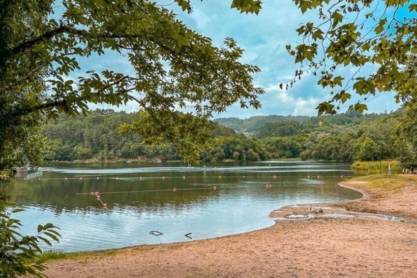 A lake with a sandy shore, surrounded by trees and hills. 5