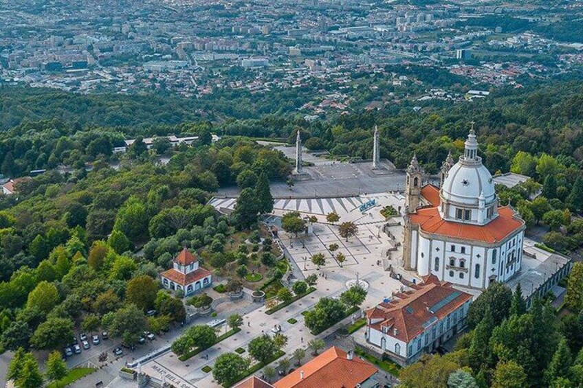 An aerial view of a city with a prominent white church with a dome, surrounded by greenery and a smaller building with a red roof. 3