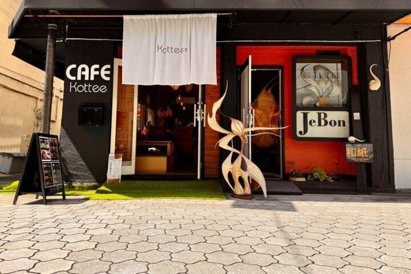 A cafe named 'Cafe Kottee' with a distinctive sign and a large decorative piece outside. 2