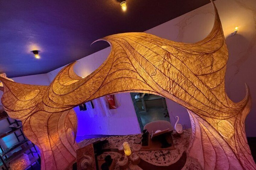 A room with a large, illuminated, leaf-like structure. 3