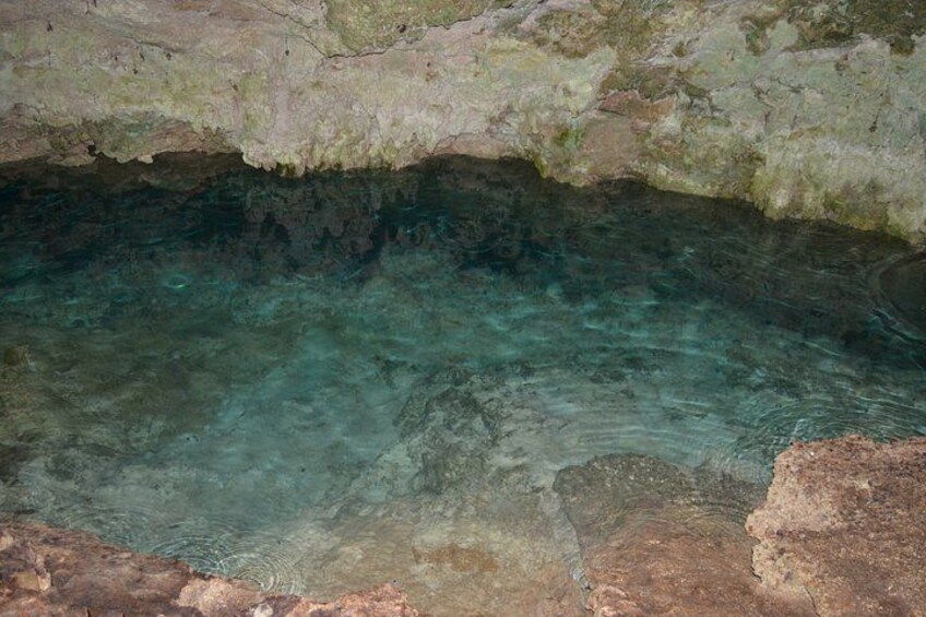 A natural pool with clear water, surrounded by rocky terrain. 3